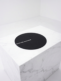 Round black mat with 'synergy sounds' logo on a white marble surface